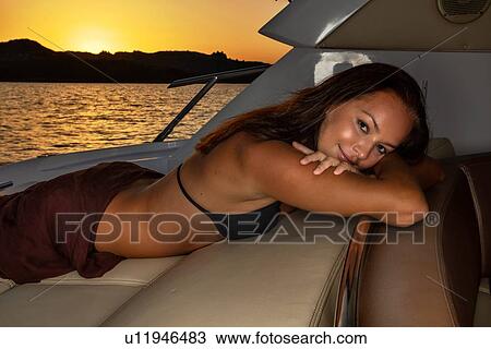 Woman in bikini relaxing on yacht at sunset View Large Photo Image Stock Image - Woman in bikini relaxing on yacht at sunset. Fotosearch