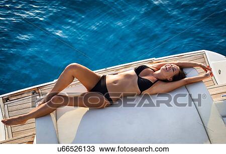 Stock Image - Woman in bikini relaxing on yacht. Fotosearch