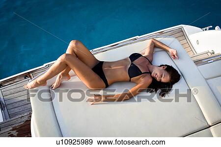 Stock Photo - Woman in bikini relaxing on yacht. Fotosearch