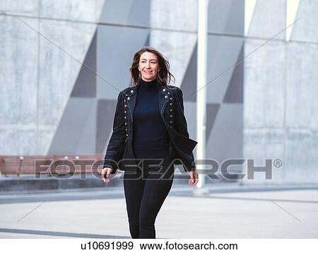 Woman in black suit walking in city View Large Photo Image Stock Photo - Woman in black suit walking in city. Fotosearch