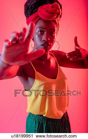 Stock Image - Woman in headscarf with arms reaching out against pink background. Fotosearch