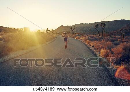 Stock Photo - Woman jogging on country road at sunset, Joshua Tree, California, USA. Fotosearch