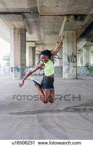 Stock Image - Woman jumping in mid air in city. Fotosearch