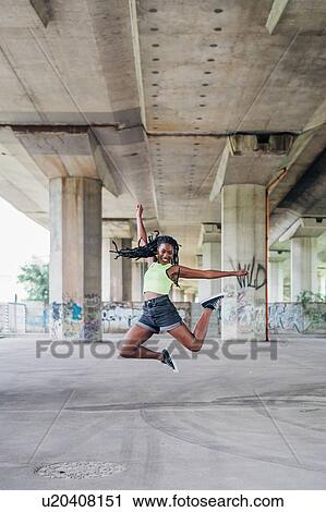 Woman jumping in mid air in city View Large Photo Image Stock Image - Woman jumping in mid air in city. Fotosearch