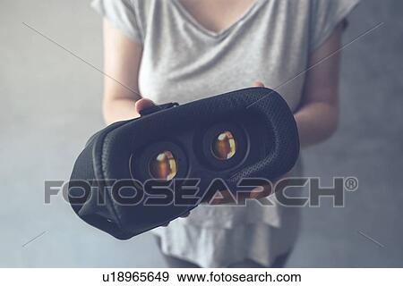 Stock Photo - Woman offering VR headset. Fotosearch
