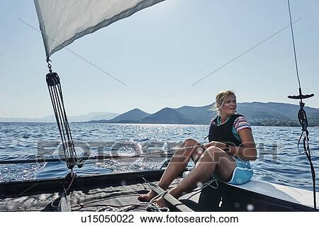 Stock Image - Woman on sailboat in sea off Paleros, Greece. Fotosearch