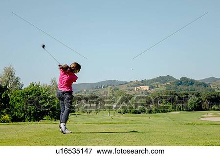 Stock Photo - Woman playing golf on golf course. Fotosearch