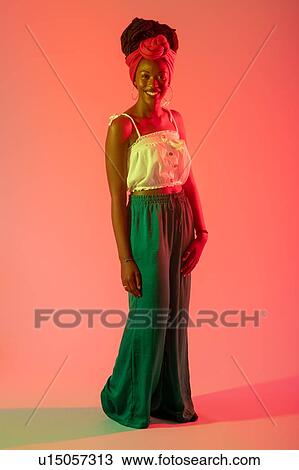 Stock Image - Woman posing against peach background. Fotosearch