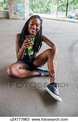 Stock Image - Woman reading text message on smartphone in city. Fotosearch