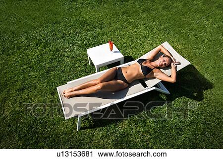 Woman relaxing in deckchair on lawn View Large Photo Image Stock Image - Woman relaxing in deckchair on lawn. Fotosearch