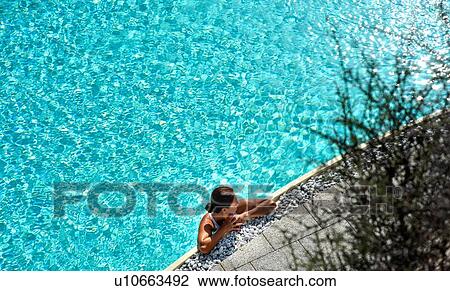 Stock Image - Woman relaxing in swimming pool. Fotosearch