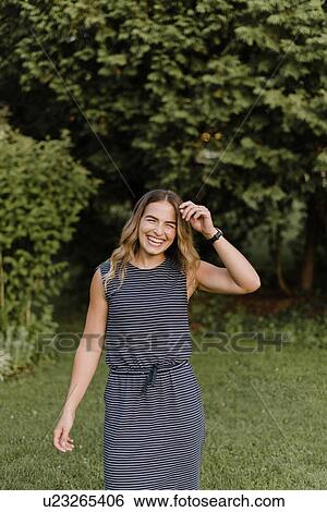 Stock Photograph - Woman standing on grass lawn in garden. Fotosearch