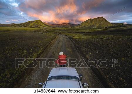 Picture - Woman traveller enjoying scenic view of volcanic mountains on vehicle, Landmannalaugar, Highlands, Iceland. Fotosearch