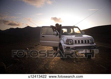 Stock Image - Woman traveller enjoying scenic view beside vehicle, Landmannalaugar, Highlands, Iceland. Fotosearch