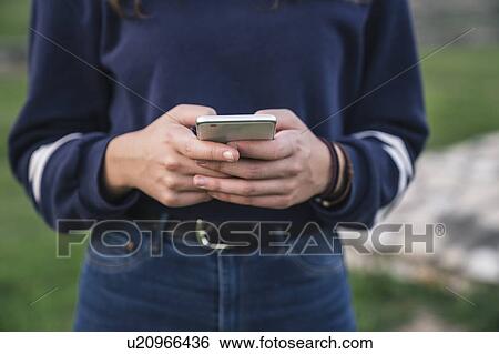 Stock Photograph - Woman using smartphone in park. Fotosearch