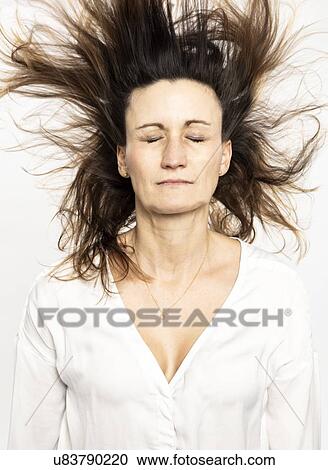 Stock Image - Woman with flying hair closing eyes, white background. Fotosearch