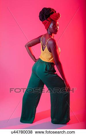 Stock Photo - Woman with headscarf posing against pink background. Fotosearch
