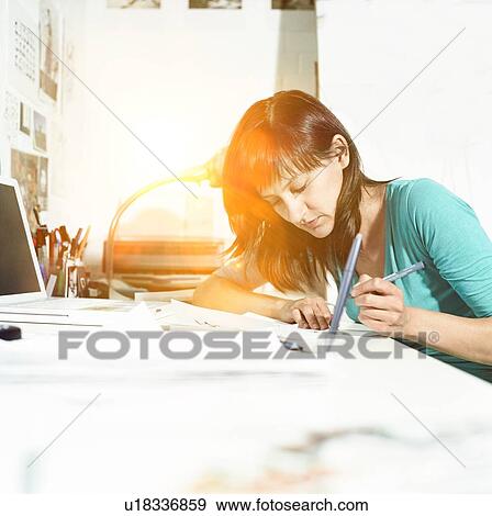 Stock Photo - Woman Working from home at Desk with lens flare in background. Fotosearch