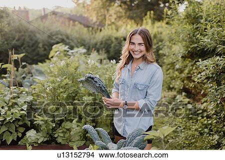 Woman working on plants and vegetables in her garden View Large Photo Image Picture - Woman working on plants and vegetables in her garden. Fotosearch