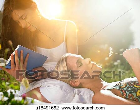 Women in meadow, one reading book View Large Photo Image Stock Image - Women in meadow, one reading book. Fotosearch