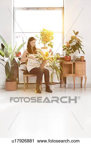 Stock Image - Women with potted plants at home office. Fotosearch