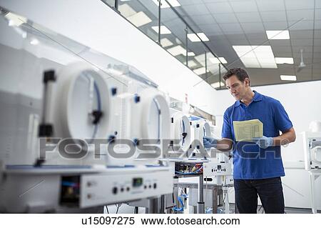 Stock Photography - Worker inspecting laboratory cabinet machines on production line in medical science factory. Fotosearch