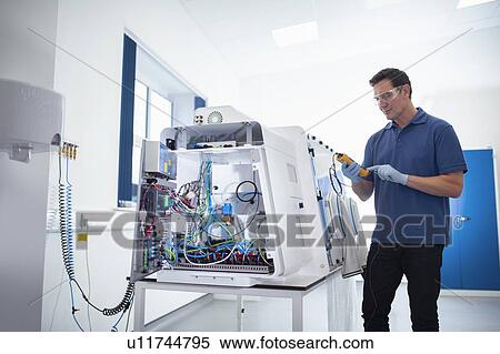 Stock Photography - Worker testing laboratory cabinet on production line in medical science factory. Fotosearch