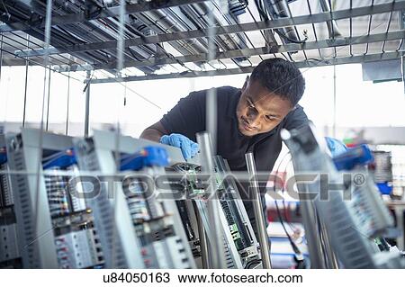Worker with electronic parts on racks in electronics assembly factory View Large Photo Image Stock Image - Worker with electronic parts on racks in electronics assembly factory. Fotosearch