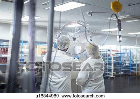 Stock Photo - Workers assembling operating theatre lighting in electronics assembly factory. Fotosearch