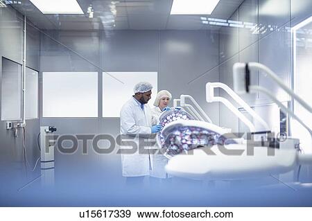 Workers in clean room assembling operating theatre lighting in electronics assembly factory View Large Photo Image Stock Photo - Workers in clean room assembling operating theatre lighting in electronics assembly factory. Fotosearch