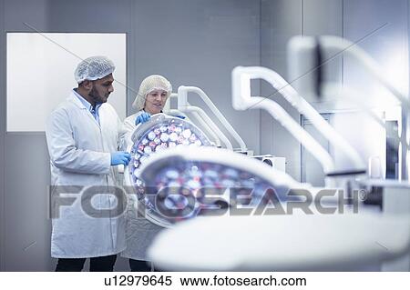 Stock Photography - Workers in clean room assembling operating theatre lighting in electronics assembly factory. Fotosearch