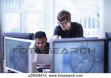 Stock Photography - Workers looking at screens in office in electronics assembly factory. Fotosearch