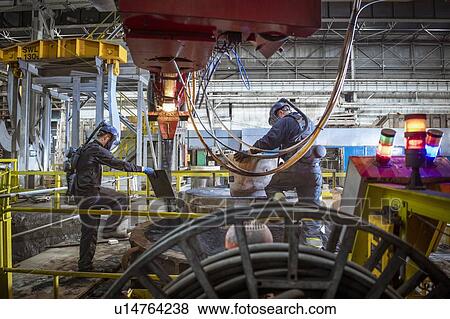 Stock Photo - Workers making sand mould for pouring molten steel into steelworks. Fotosearch