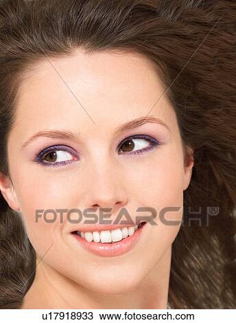 Stock Image - Young brunette Woman Smiling with purple eye make up. Fotosearch