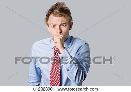 Stock Image - Young businessman coughing and looking into camera. Fotosearch