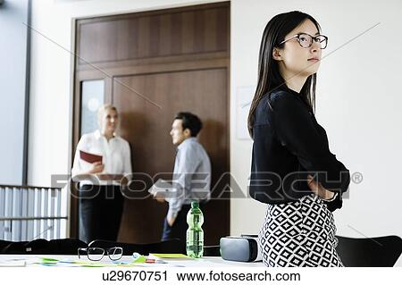 Young businesswoman in office, colleagues talking in background View Large Photo Image Stock Image - Young businesswoman in office, colleagues talking in background. Fotosearch