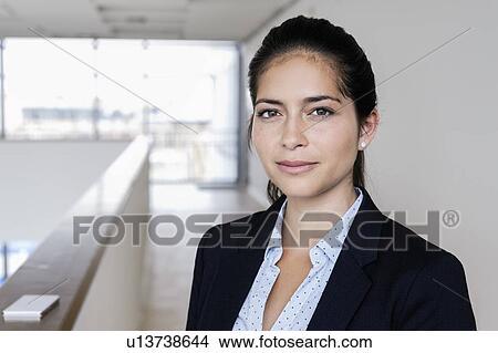 Picture - Young businesswoman taking break at corridor of office building. Fotosearch