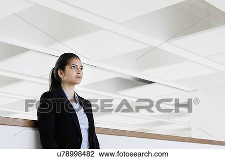 Stock Image - Young businesswoman taking break at corridor of office building. Fotosearch