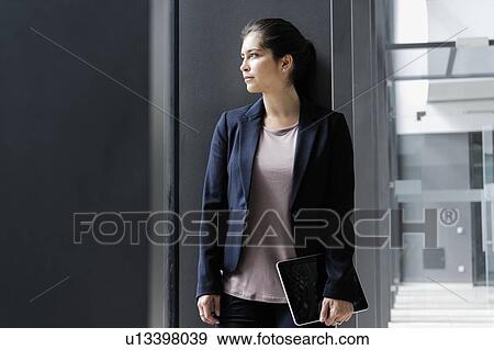 Young businesswoman taking break at corridor of office building View Large Photo Image Stock Photo - Young businesswoman taking break at corridor of office building. Fotosearch