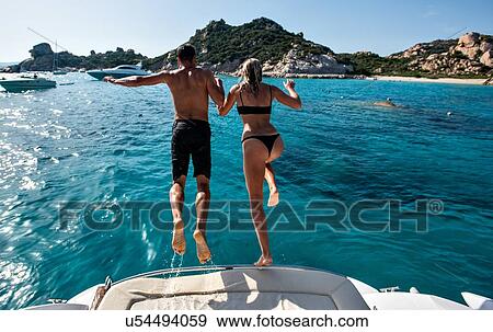 Stock Photo - Young couple jumping into sea from yacht, La Maddalena island, Sardegna, Italy. Fotosearch