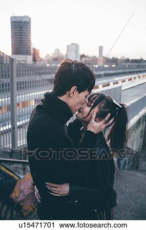 Stock Image - Young couple kissing in train station, Milan, Italy. Fotosearch