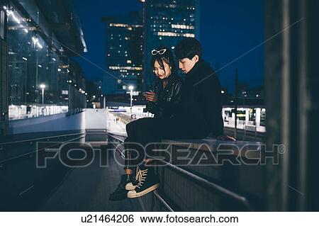 Stock Photograph - Young couple sharing text in train station, Milan, Italy. Fotosearch