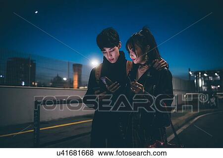 Stock Photo - Young couple sharing text on street, Milan, Italy -. Fotosearch