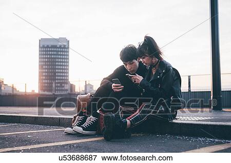 Young couple texting on kerb, Milan, Italy View Large Photo Image Stock Photo - Young couple texting on kerb, Milan, Italy. Fotosearch