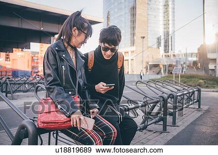 Young couple using mobile phone on bicycle racks, Milan, Italy View Large Photo Image Stock Photo - Young couple using mobile phone on bicycle racks, Milan, Italy. Fotosearch