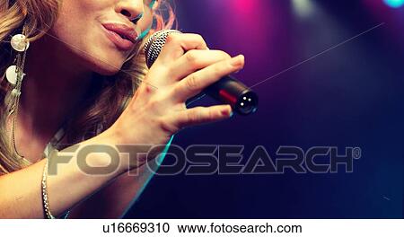 Stock Image - Young female rockstar Singing in Concert. Fotosearch