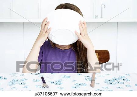 Stock Photo - Young girl drinking from bowl at kitchen table. Fotosearch