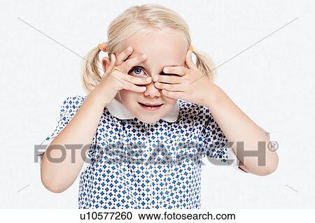 Stock Image - Young girl peering through fingers. Fotosearch