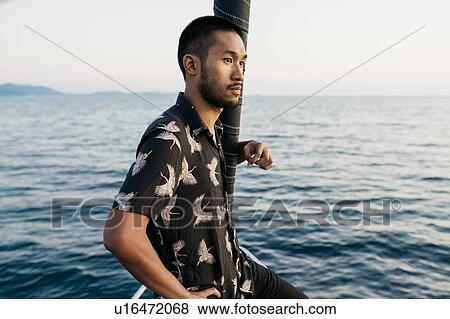 Young man on sailboat looking into distance, Italy View Large Photo Image Stock Photo - Young man on sailboat looking into distance, Italy. Fotosearch
