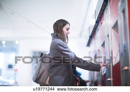 Picture - Young woman at ticket machine in train terminal. Fotosearch